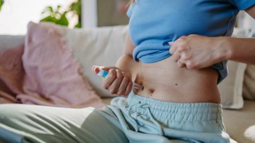 Close-up shot of a diabetic woman injecting insulin into her abdomen.